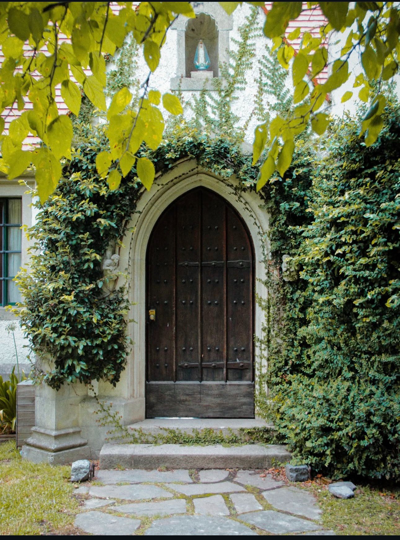Entrada principal — puerta gótica con hiedra